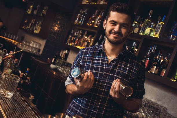 istock Young bartender standing at bar counter holding shaker playful 1164612722