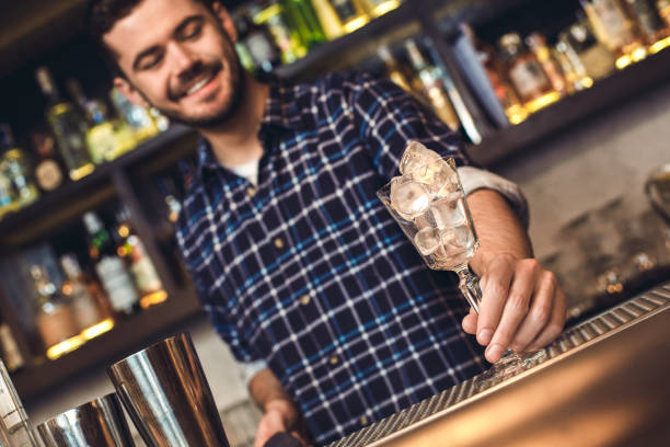 istock Young bartender standing at bar counter serving glass with ice cheerful close-up 1164612727