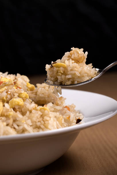 A close up of taking a spoonful of fried rice from a bowl.