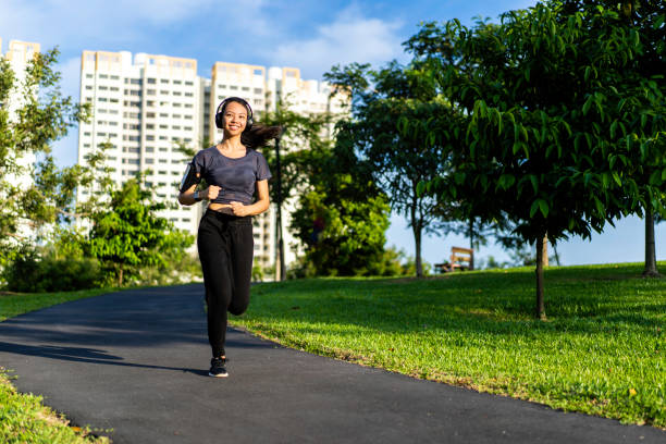 beautiful young sporty asian woman running at public park - filipino ethnicity audio imagens e fotografias de stock