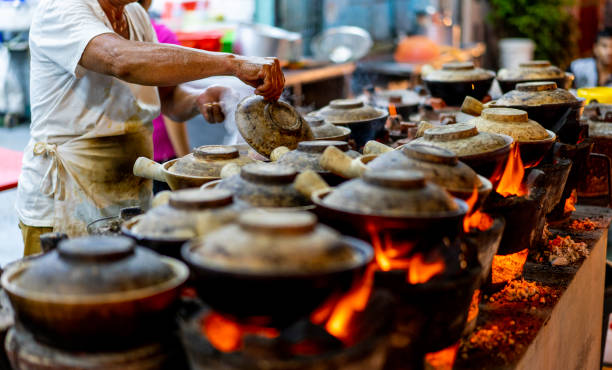 Malaysia Hawker Culture, Clay pot Chicken Rice stock photo Malaysia Street Hawker cooking Clay pot Chicken Rice in night market at Kuala Lumpur. traditional malaysian food stock pictures, royalty-free photos & images