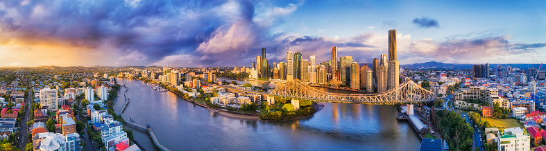 Rain and storm coming to Brisbane city CBD across Brisbane river and surrounding suburbs in mid-air panoramic view over Story bridge and horizon.