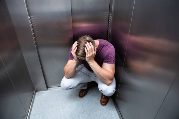 Worried Man With Hands On Head Crouched Worried Man With Hands On Head In Elevator phobia stock pictures, royalty-free photos & images