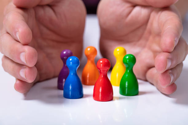 istock Person Protecting Multicolored Pawns 1164644234