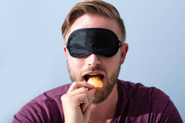 hombre con los ojos vendados que prueban alimentos - venda de ojos fotografías e imágenes de stock