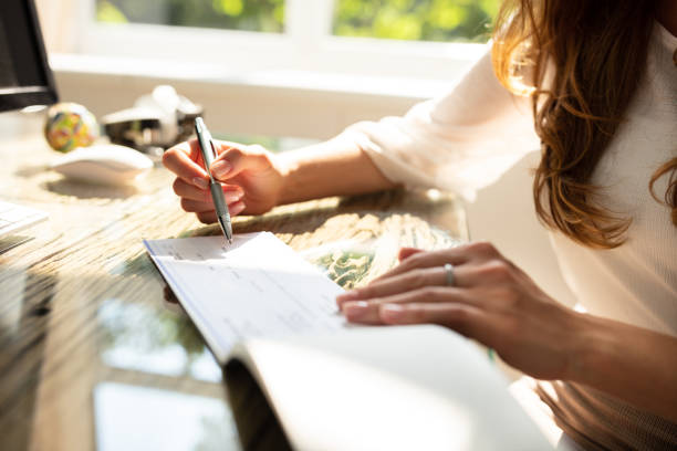 Businesswoman Signing Cheque Businesswoman's Hand Signing Cheque On Wooden Desk cheque financial item stock pictures, royalty-free photos & images