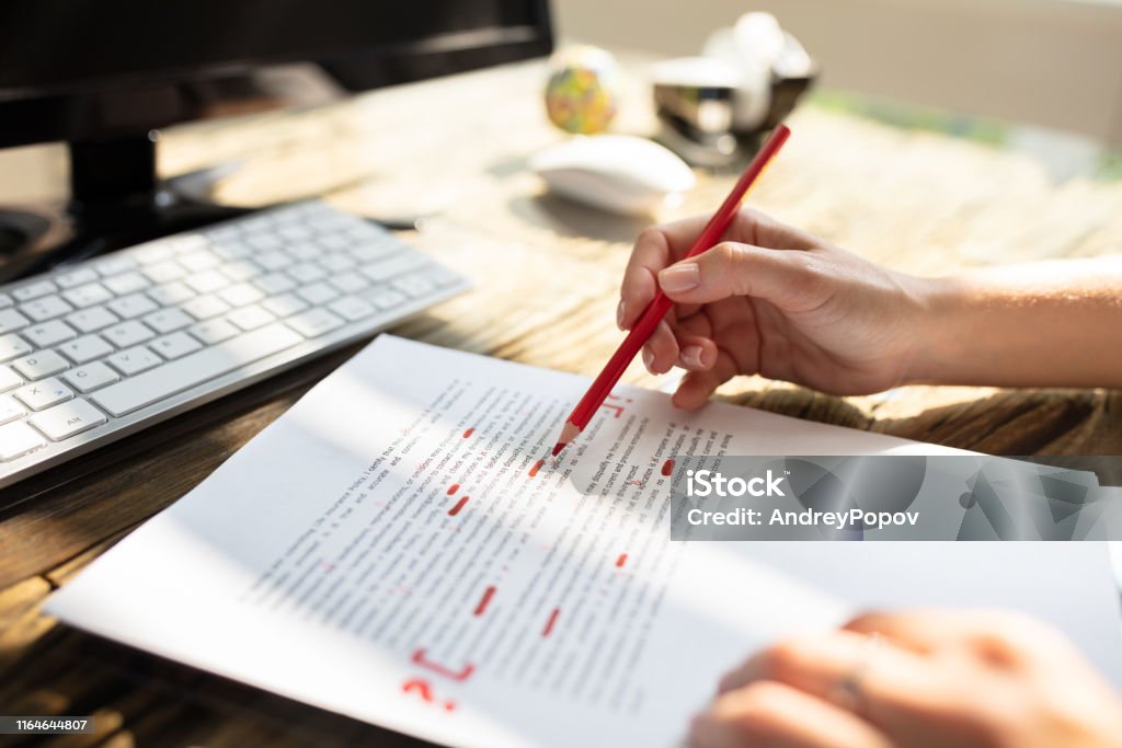 Person Marking Error With Red Marker Close-up Of A Person's Hand Marking Error With Red Marker On Document Editor Stock Photo