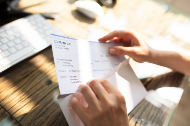 Businessperson Opening Envelope With Paycheck Close-up Of A Businessperson's Hand Opening Envelope With Paycheck Over Wooden Desk cheque financial item stock pictures, royalty-free photos & images