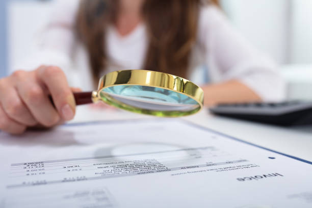 istock Businesswoman Looking Invoice Through Magnifying Glass 1164644862