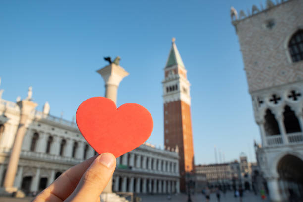 istock Person's Hand Holding Heart Shape In Front Of Bell Tower 1164645849