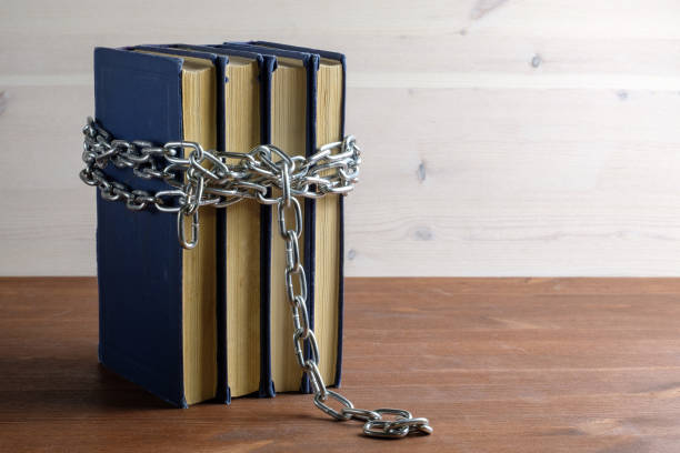 istock chain and books on a wooden table separating a light and dark background 1164647406