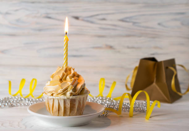 istock Happy birthday cupcake with lit candle and a present 1164647631