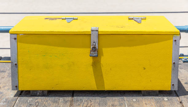Yellow old wood box locked with rusty padlock. Bright yellow wood trunk on wooden deck, Santa Monica pier, California