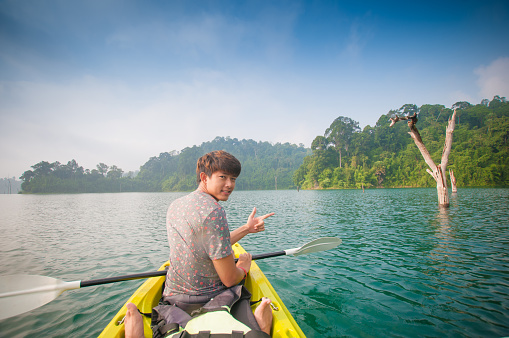 Young Asia man paddling kayak at lake in Chiewlarn Surat Thani Thailand