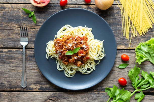 istock Spaghetti on black plate on wooden background. top view 1164653768