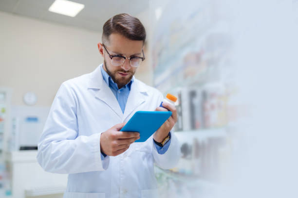 istock Attentive brunette apothecary staring at screen of tablet 1164653918
