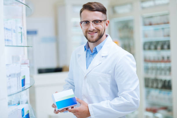 istock Cheerful bearded chemist presenting new package of pills 1164654014