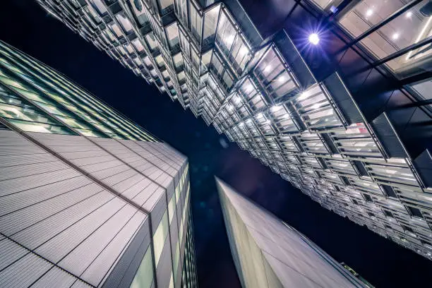 Highly detailed abstract wide angle view up towards the sky in the financial district of London City and its ultra modern contemporary buildings with unique contemporary architecture during night time. Shot on Canon EOS R full frame with 14mm wide angle prime lens. Image is ideal for background with copy space and no people.