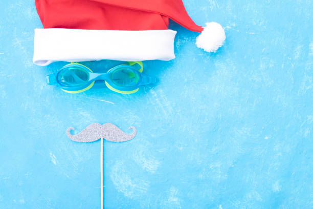Red christmas hat and sunglasses near the pool. Place for text. stock photo