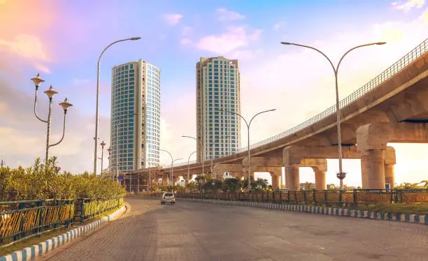 Tall city buildings with under construction over bridge alongside highway road at Rajarhat, Kolkata India.