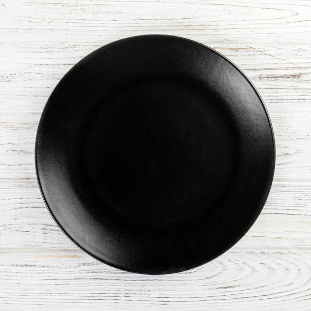 istock Black round plate on wooden background, top view, copy space 1164663022