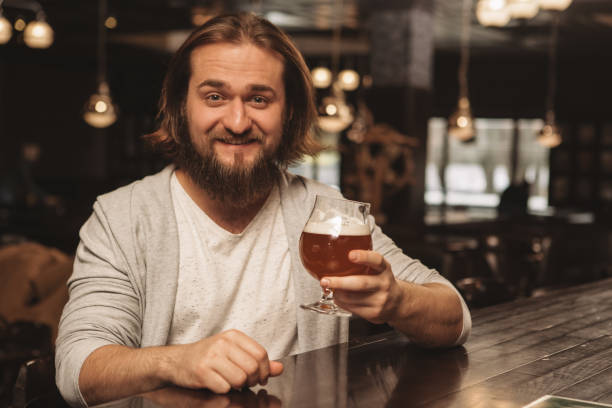 istock Young man drinking beer at the bar 1164667587