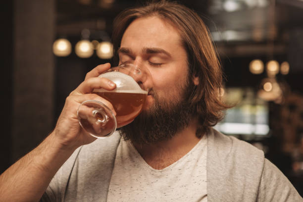 istock Young man drinking beer at the bar 1164667588