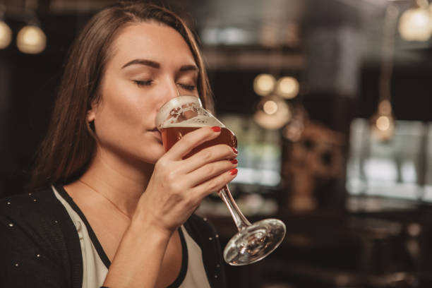 hermosa mujer bebiendo cerveza en el pub - cerveza tipo ale fotografías e imágenes de stock