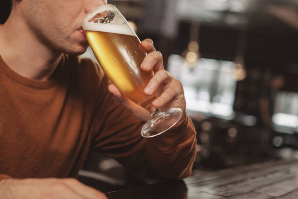istock Young man drinking beer at the bar 1164668198