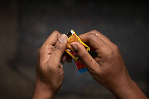 インドでチューイングタバコ、グッカ、ガ�ッカを引き裂く男の手のクローズアップ。 - manually ストックフォトと画像