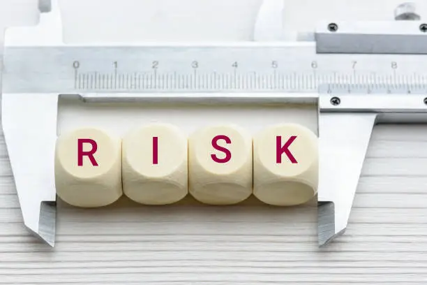 Risk assessment / risk analysis and management concept : Words RISK on wood blocks and a vernier caliper with scales, depict evaluation for financial risk of an investor involved in stock, bond market