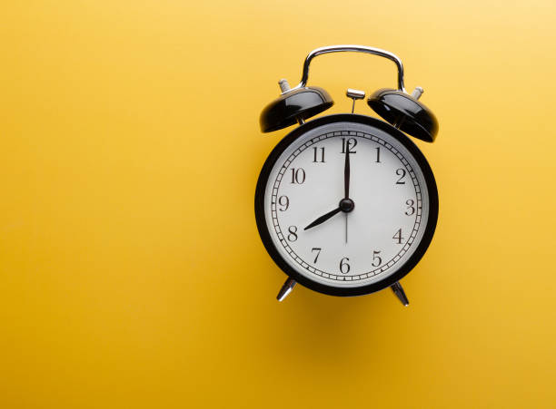 istock Alarm clock on yellow background top view. Concept of time. 1164669650