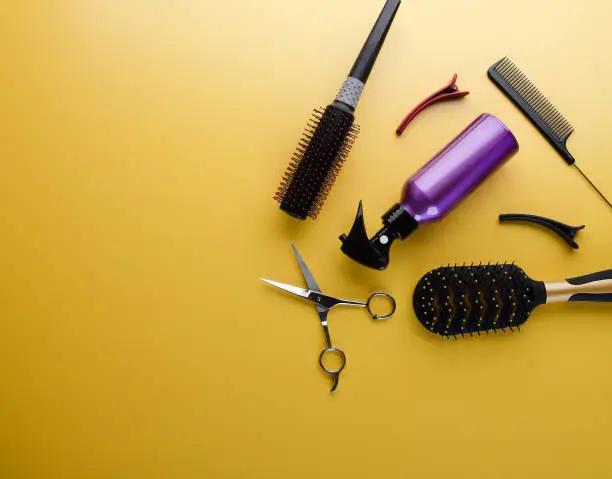 Photo of Top view of professional hair dresser tools on yellow background