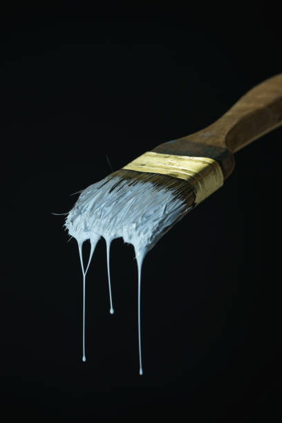 istock Dripping white paint  of old brush on a black background. 1164673361