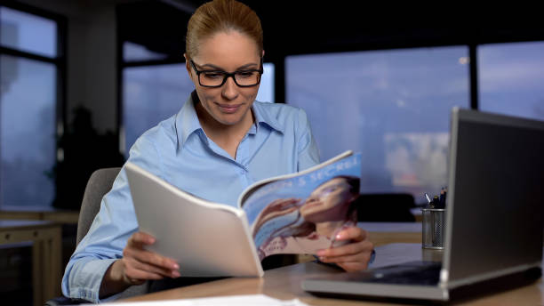 istock Lazy secretary reading magazine in office, wasting time and avoiding work 1164673383