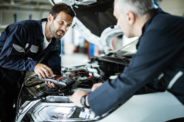 istock Auto mechanics talking while working with car diagnostic tool in a repair shop. 1164676457