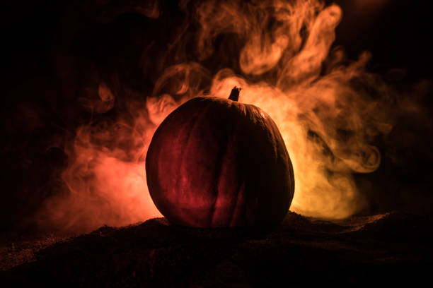 istock Halloween theme with pumpkin against smoky dark background. Empty space for text 1164677193