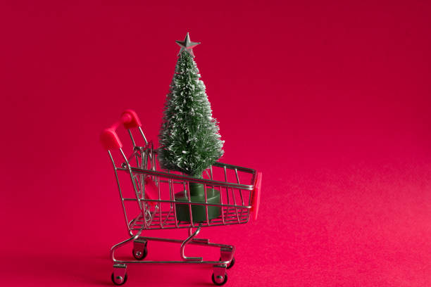 istock small bauble christmas tree in a shopping cart on a pink background 1164677638