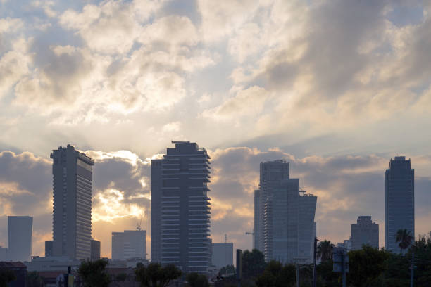 Sunrise over modern office buildings in business district center of Tel Aviva. Morning time. Skyline view of cityscape with sunlight and flare in warm light color tone.