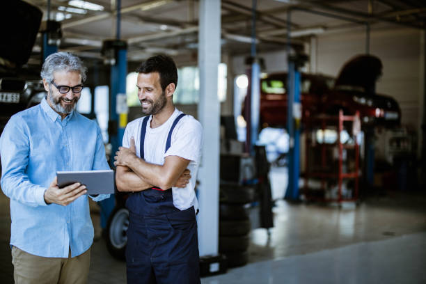 szczęśliwy menedżer i mechanik za pomocą tabletu cyfrowego w warsztacie samochodowym. - auto repair shop customer auto mechanic mechanic zdjęcia i obrazy z banku zdjęć