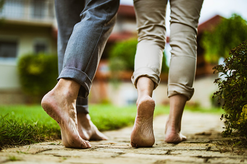 De cerca de pareja irreconocible caminando descalzo en el patio trasero. photo