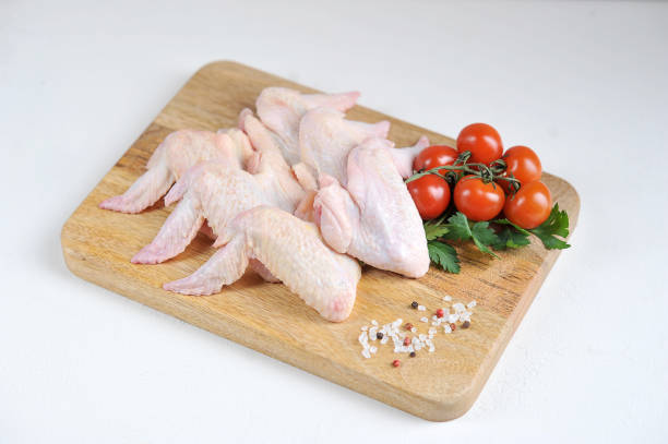 istock Raw chicken wings on a wooden board. The composition is complemented by cherry tomatoes, parsley and spices. 1164678955