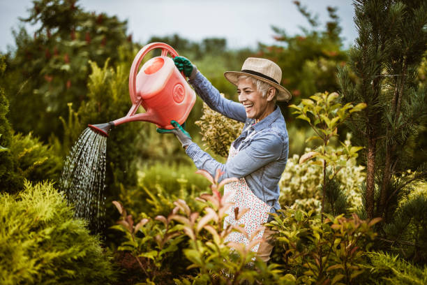 Happy senior woman enjoying while watering her plants.