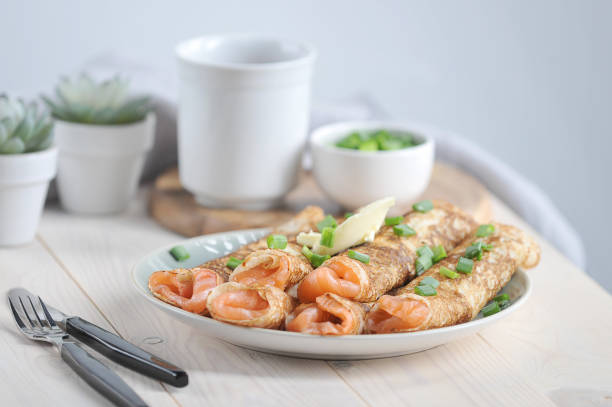 pancakes with salmon. pancakes sprinkle with green onions. next to the plate are cutlery. - close up cookie gourmet food imagens e fotografias de stock