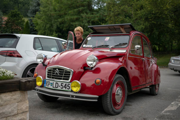 eine frau, die den ehrwürdigen citroen 2cv betritt - venerable stock-fotos und bilder