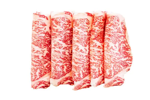 Isolated Premium Rare Slices Wagyu A5 beef with high-marbled texture on square wooden plate served for Sukiyaki and Shabu.