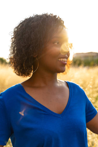 Pretty young woman dressed in blue, walking in a yellow field on summer. stock photo