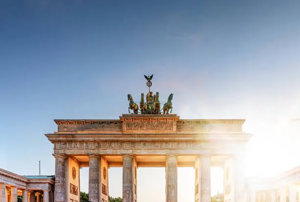 Brandenburg Gate monument as seen from Pariser Platz in Berlin, Germany during sunset on clear summer day