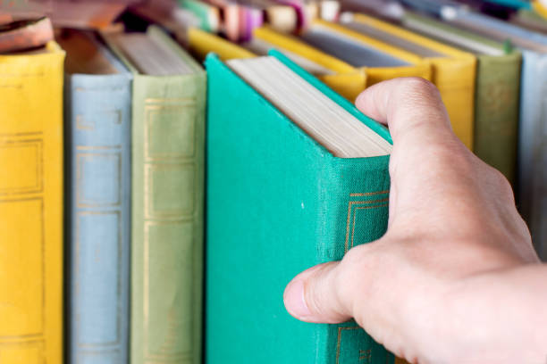 istock Image of a hand choosing a book from a bookshelf 1164684701