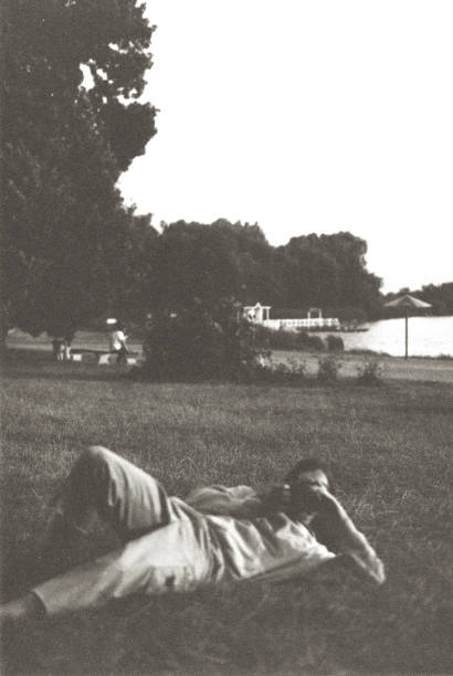 Film photo of man taking picture on old-fashioned film camera Film photo of man laying on grass and taking picture on old-fashioned film camera photographic film camera stock pictures, royalty-free photos & images